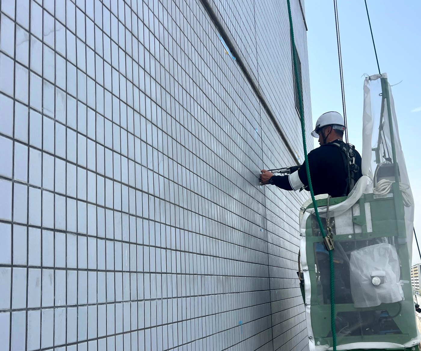 高所作業で外壁タイルを補修する作業員